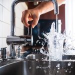 a water glass being filled at a kitchen sink