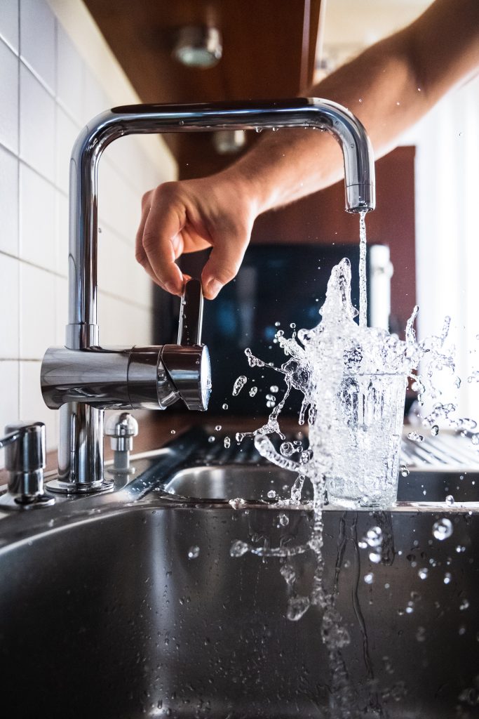 a water glass being filled at a kitchen sink